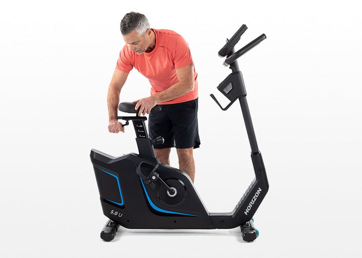 User adjusting the Horizon 5.0U upright exercise bike before a workout.