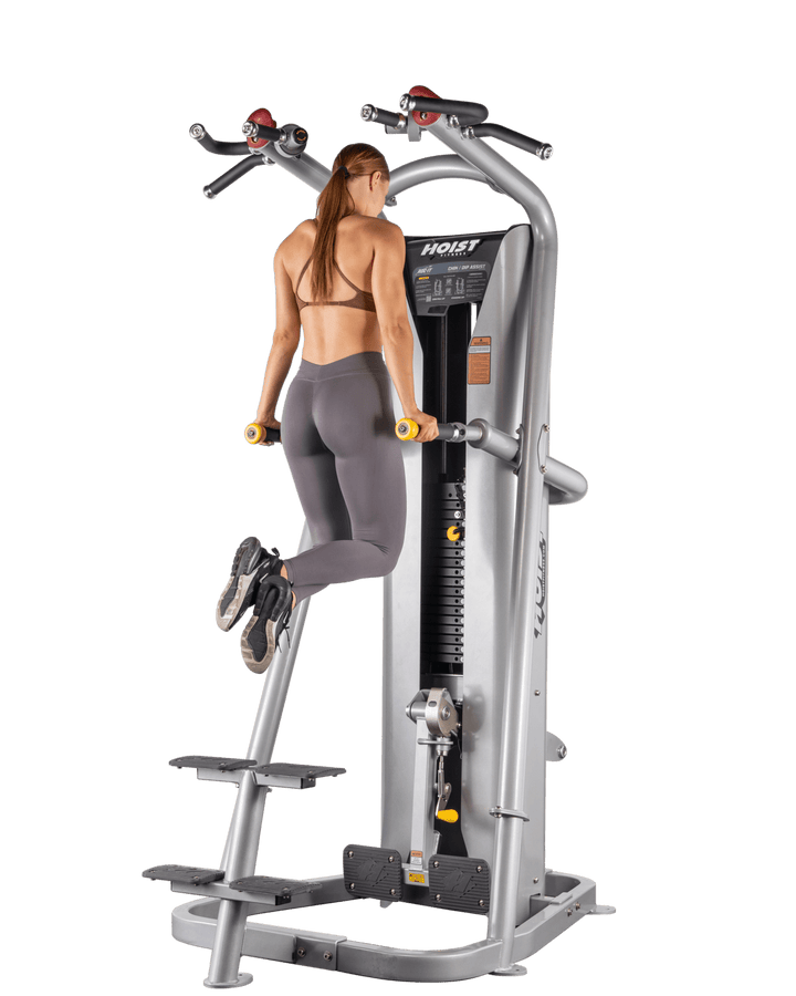 woman using knee pad on chin assist machine preparing for assisted pull-up exercise
