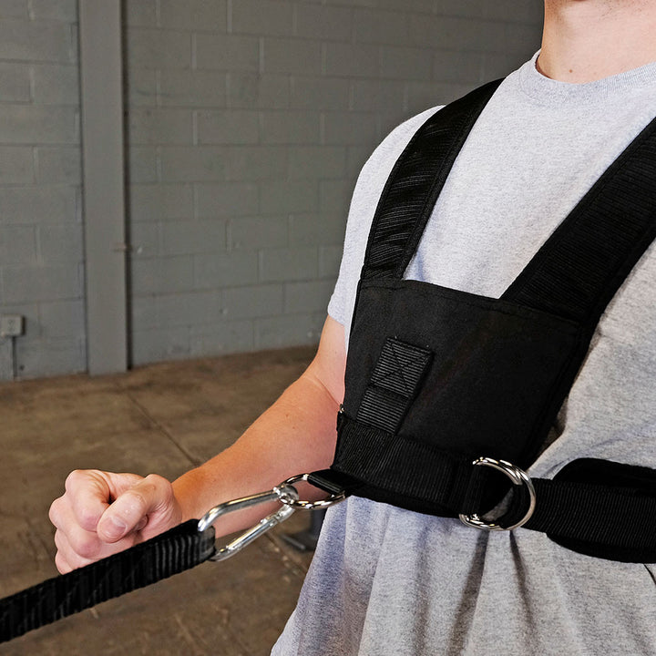 Front view of athlete wearing the Body-Solid BSTSH adjustable sled harness with resistance attached