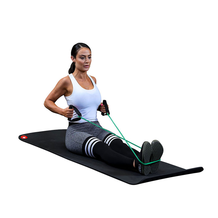 Woman performing a seated exercise on a mat with a Body-Solid resistance tube