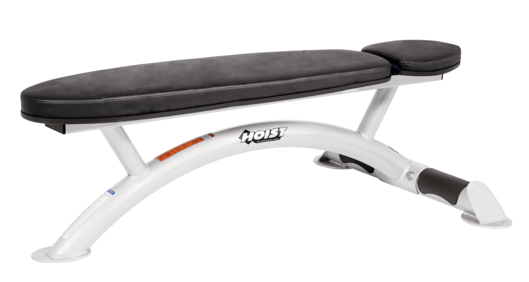 Hoist commercial flat bench with white black padding and curved steel frame for weightlifting and strength training