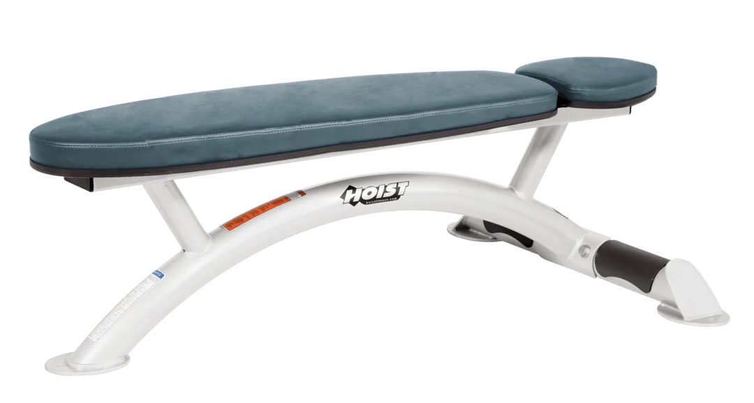 Hoist commercial flat bench with white blue ridge padding and curved steel frame for weightlifting and strength training