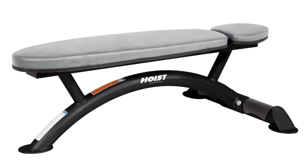 Hoist commercial flat bench with dove grey padding and curved steel frame for weightlifting and strength training