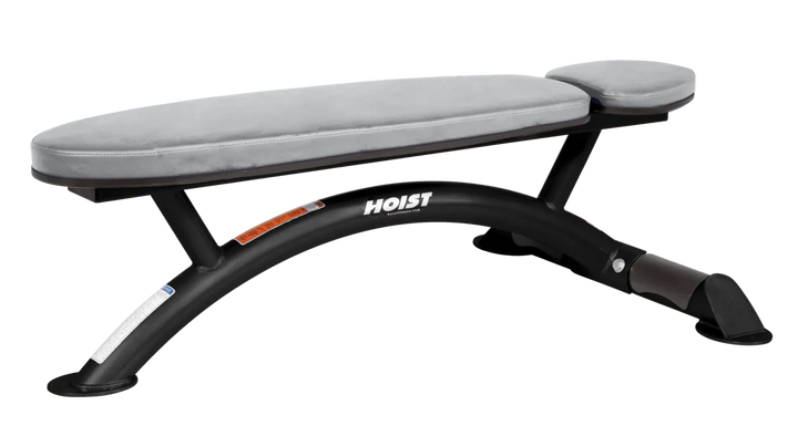 Hoist commercial flat bench with dove grey padding and curved steel frame for weightlifting and strength training