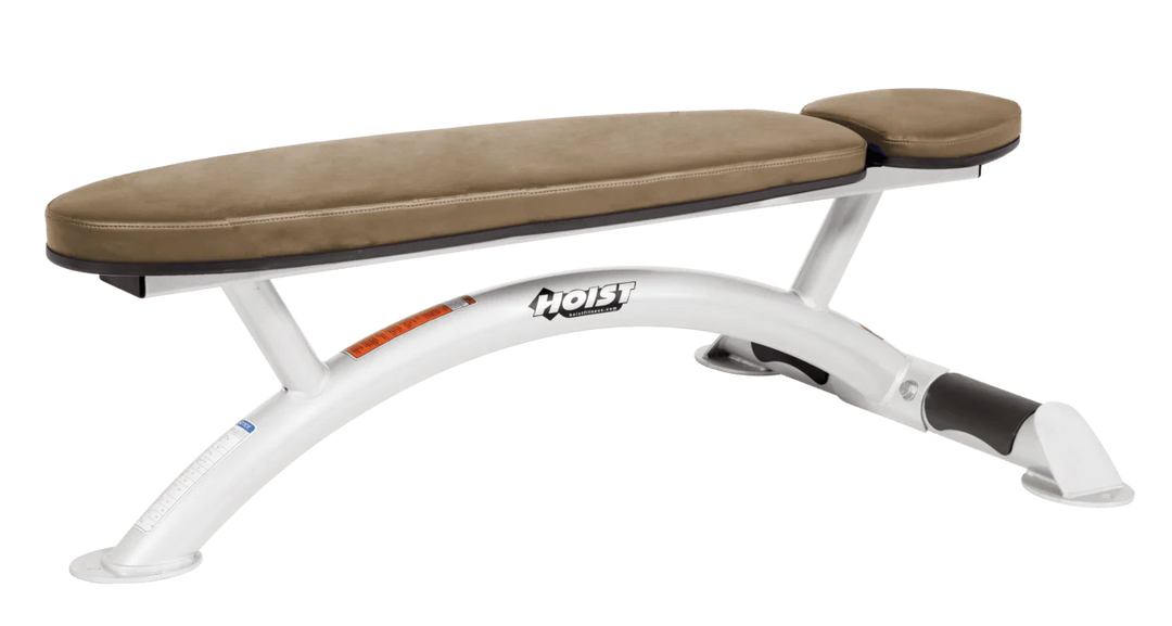 Hoist commercial flat bench with white wheat padding and curved steel frame for weightlifting and strength training