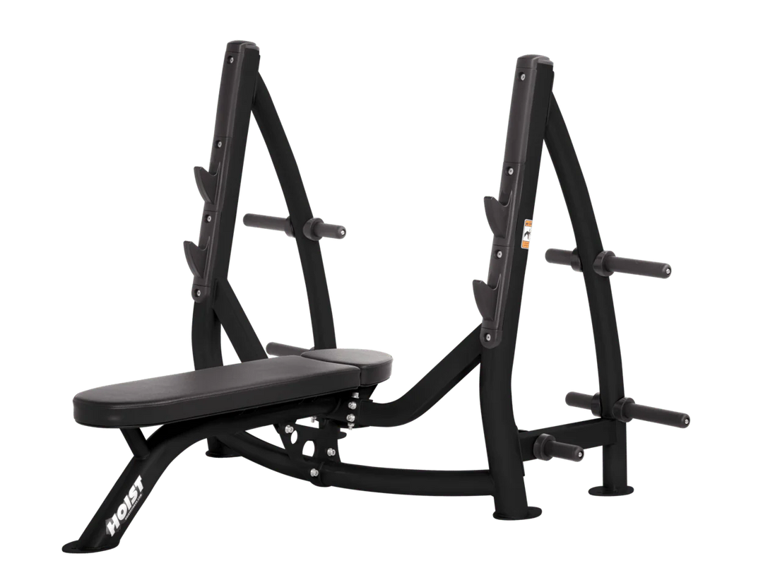 Hoist black commercial Olympic flat bench with built-in weight plate storage and barbell rack for strength training