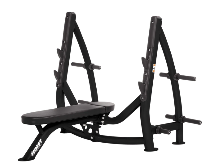 Hoist black commercial Olympic flat bench with built-in weight plate storage and barbell rack for strength training