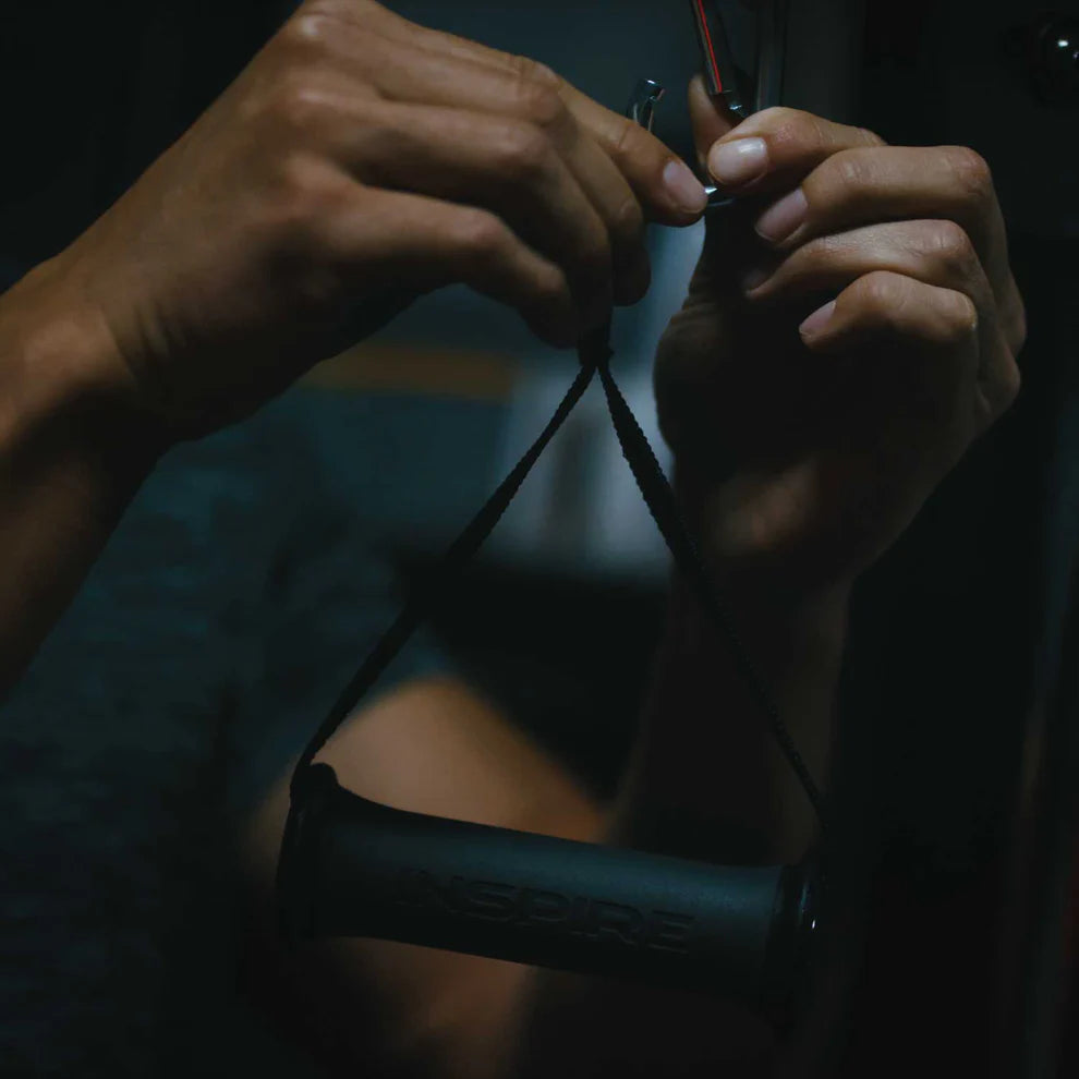 hands attaching rubber grip D handle to cable machine for workout setup
