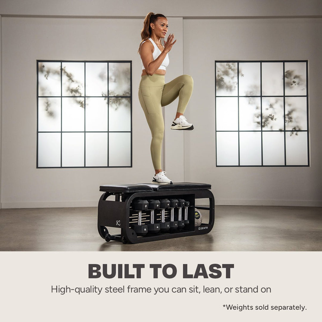 Centr Fusion workout bench used as a platform for a step-up exercise with dumbbells stored below
