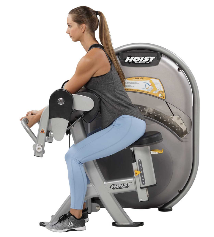 User performing seated biceps curl on machine demonstrating proper arm positioning and movement path