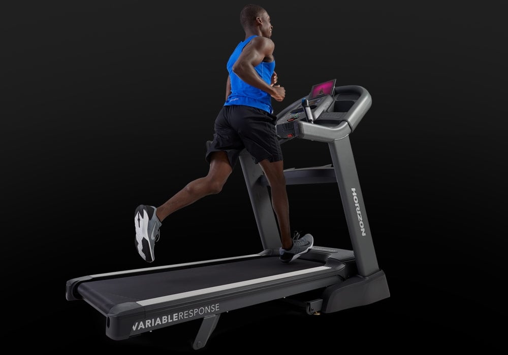 User operating the Horizon Elite 7.0 AT treadmill console and media controls.
