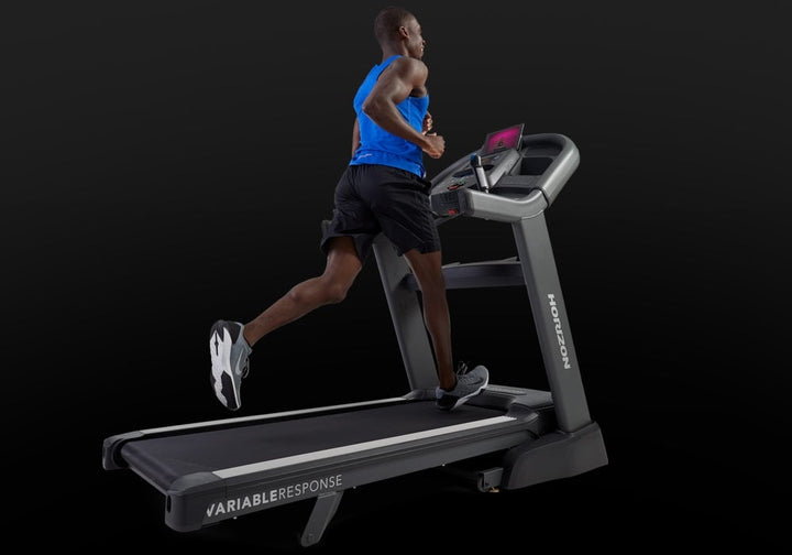 User operating the Horizon Elite 7.0 AT treadmill console and media controls.