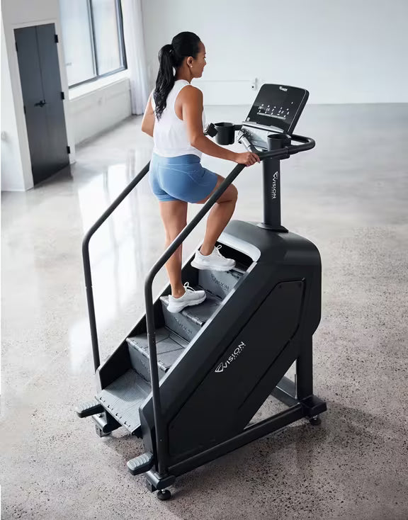 Person using the Vision Fitness Summit Stairclimber in a fitness facility with hands positioned on the handlebars