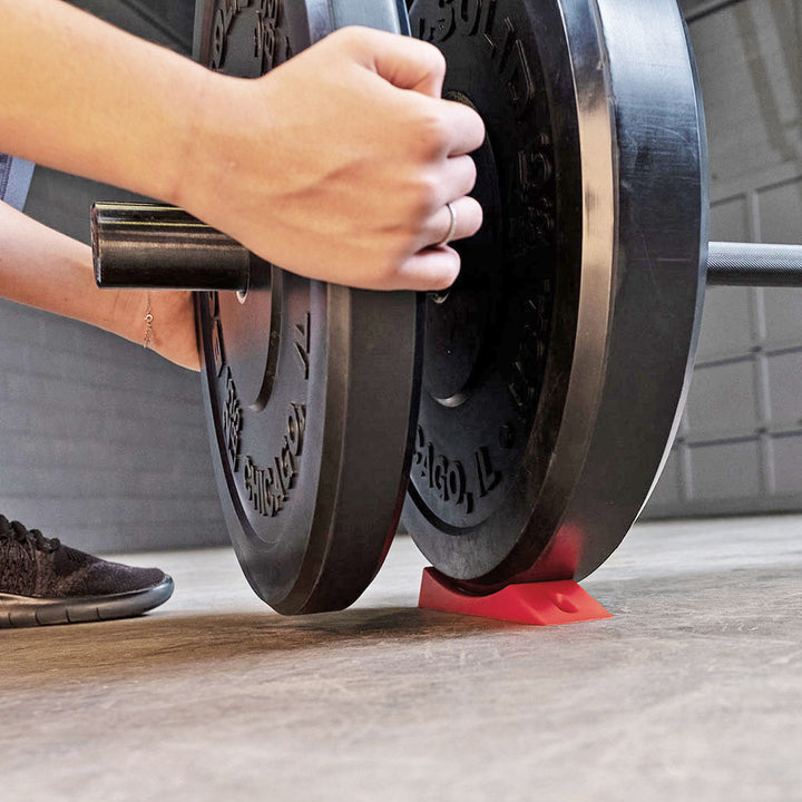 Using the deadlift wedge to raise a barbell for loading weight plates.
