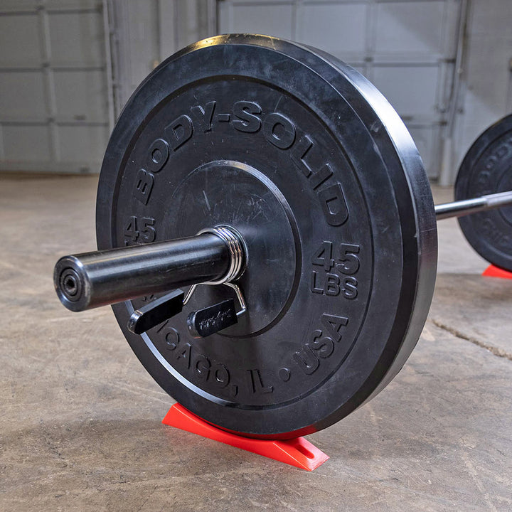 Olympic barbell resting on the Body-Solid deadlift wedge during plate changes.