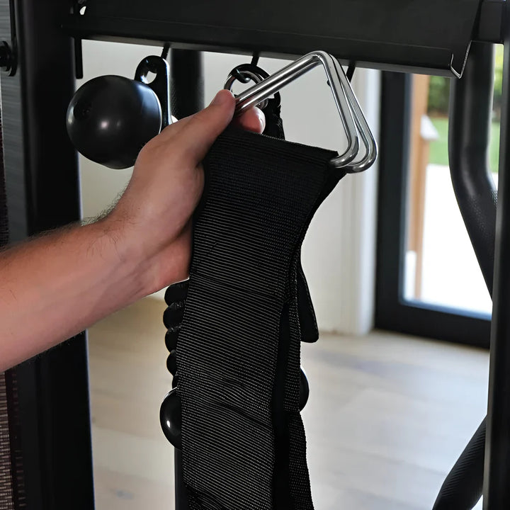 hand attaching chin dip belt strap to gym equipment for weighted exercise