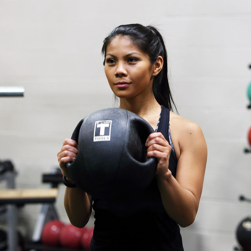 Person holding a Body-Solid dual grip medicine ball during strength training.