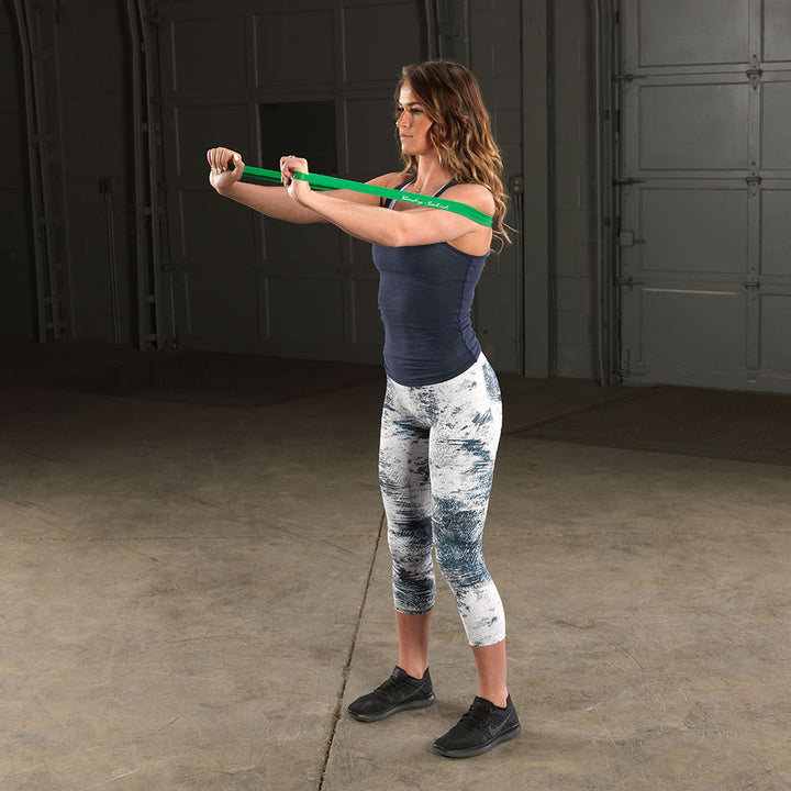 User performing a front raise exercise with a Body-Solid resistance loop band.