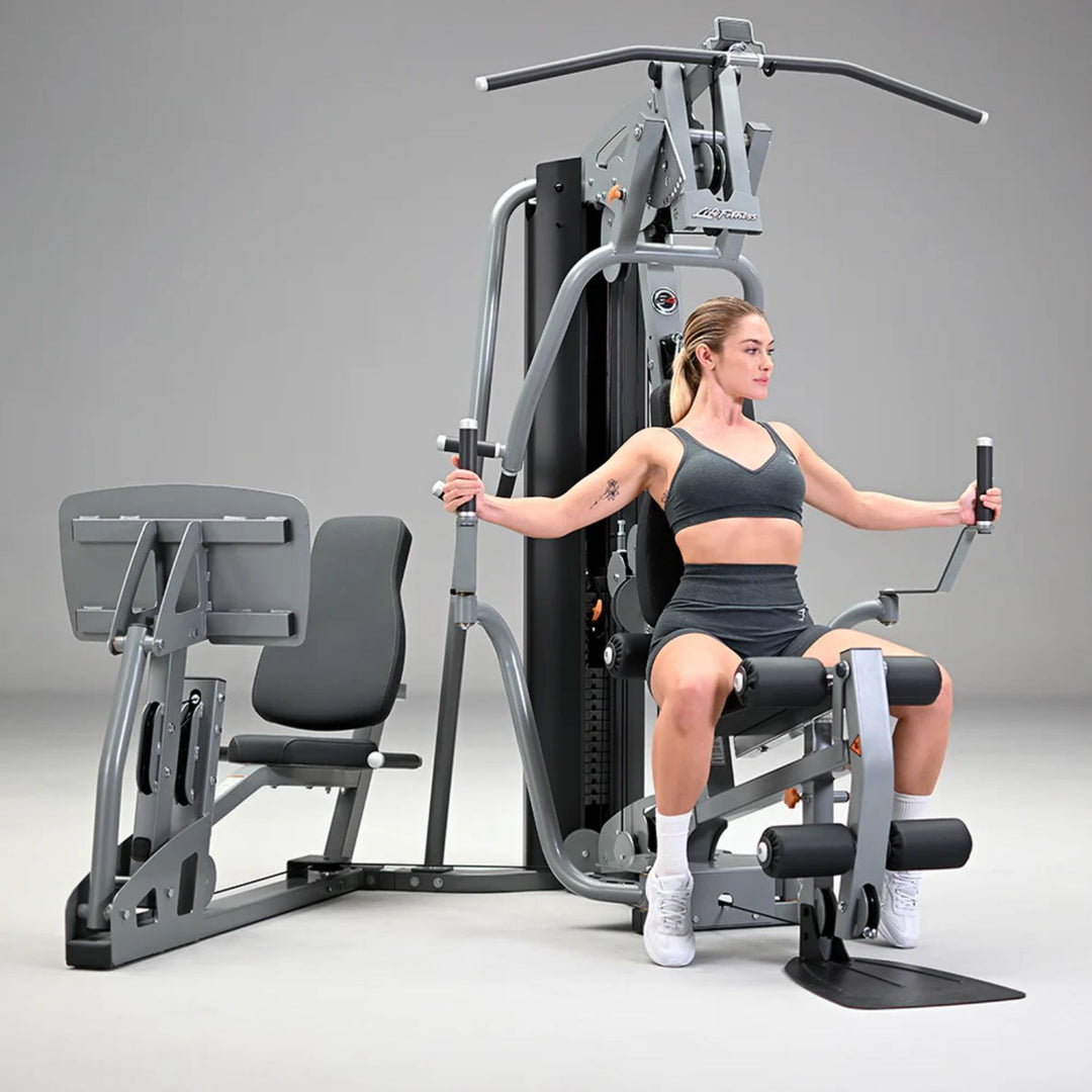 Compact home gym equipment with dual pivot arms for chest and shoulder exercises