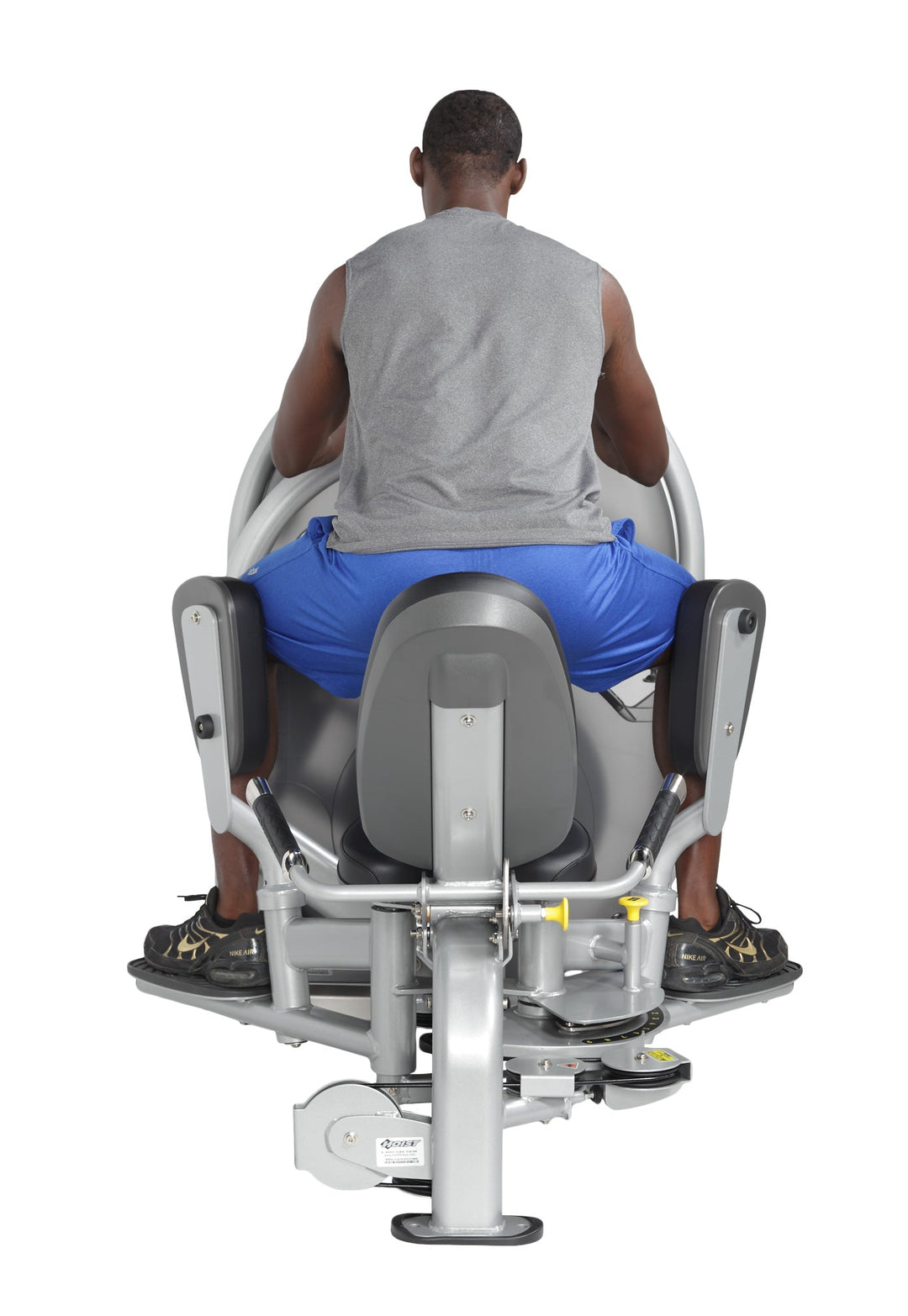 User seated performing outer thigh abduction exercise with legs pushing outward against padded supports