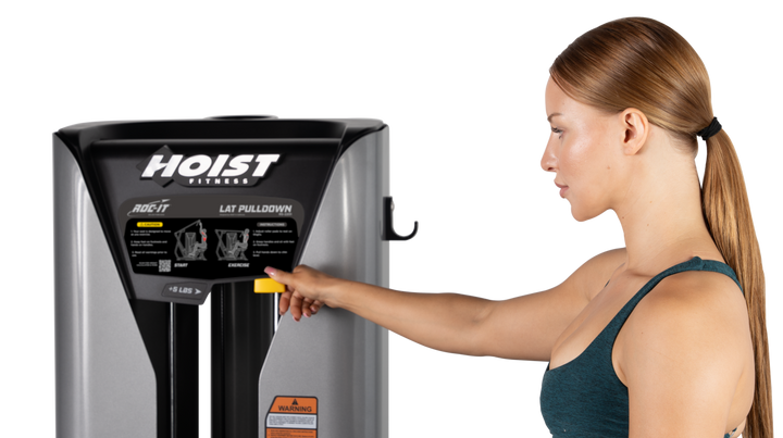 user adjusting selectorized weight stack on lat pulldown machine for customized resistance