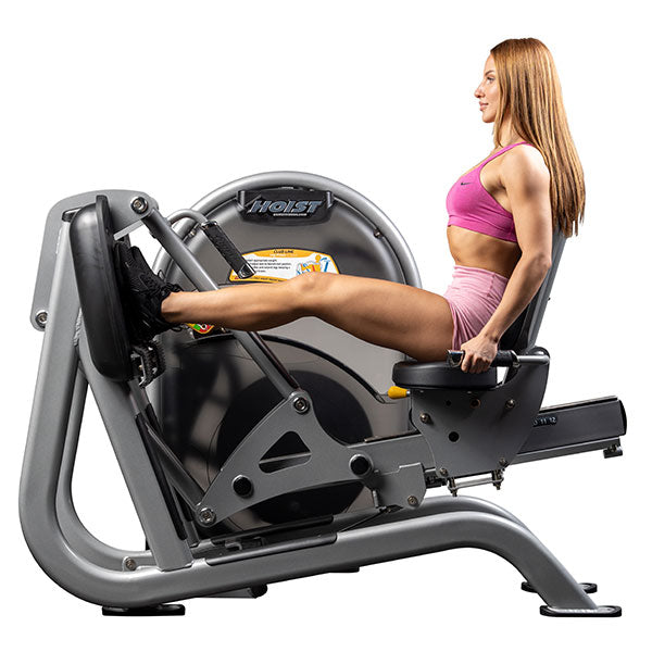 User seated on leg press machine with knees bent and feet on platform in starting position