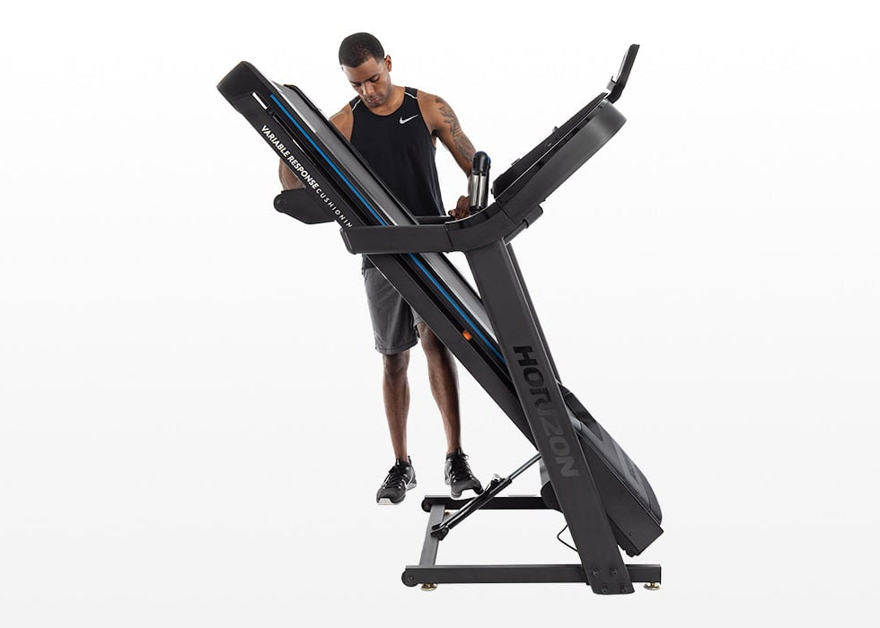 Person folding the Horizon 7.0 AT treadmill using the hydraulic folding system.