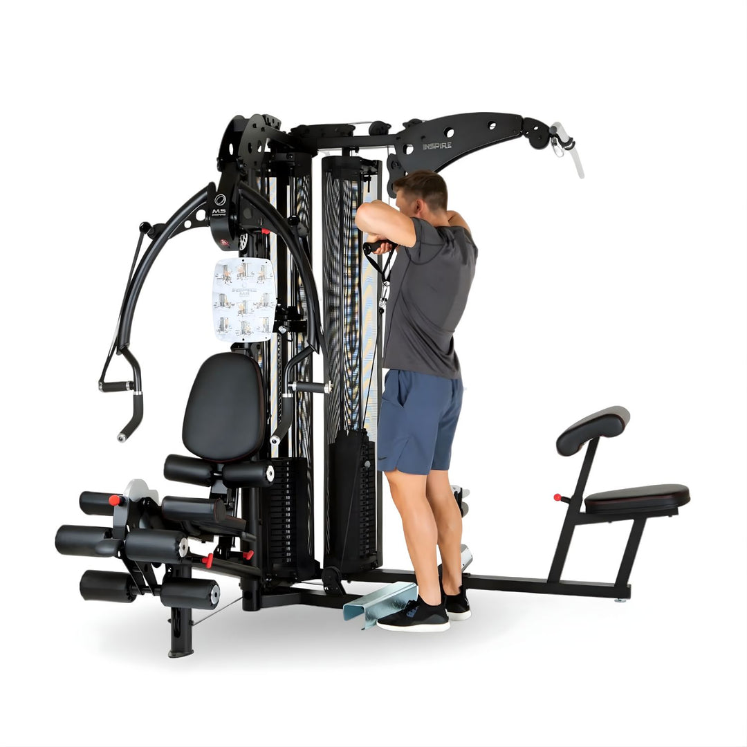 User performing triceps exercise on Inspire M5 multi gym showing cable system and full body strength training setup