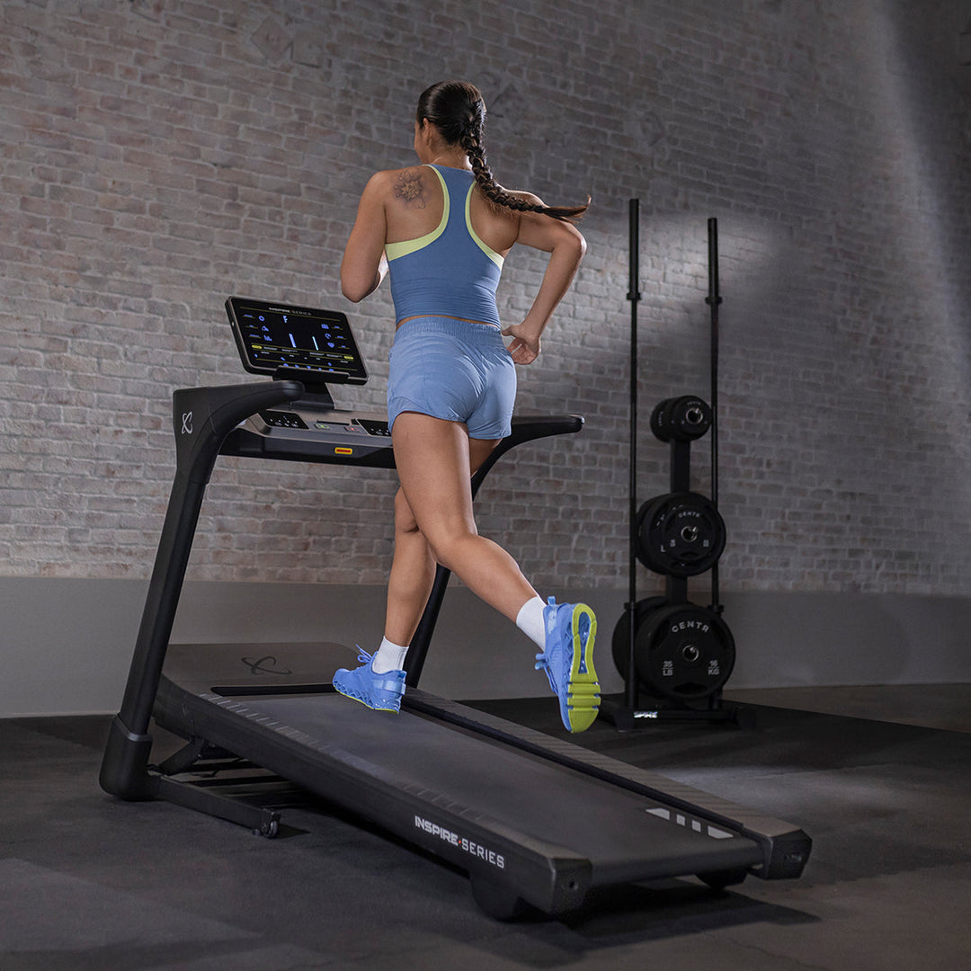 User running on Inspire T5 treadmill in home setting showing smooth running deck and ergonomic design for cardio workouts