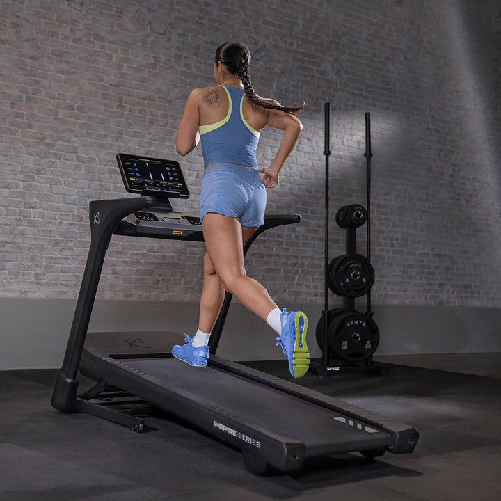 User running on Inspire T5 treadmill in home setting showing smooth running deck and ergonomic design for cardio workouts