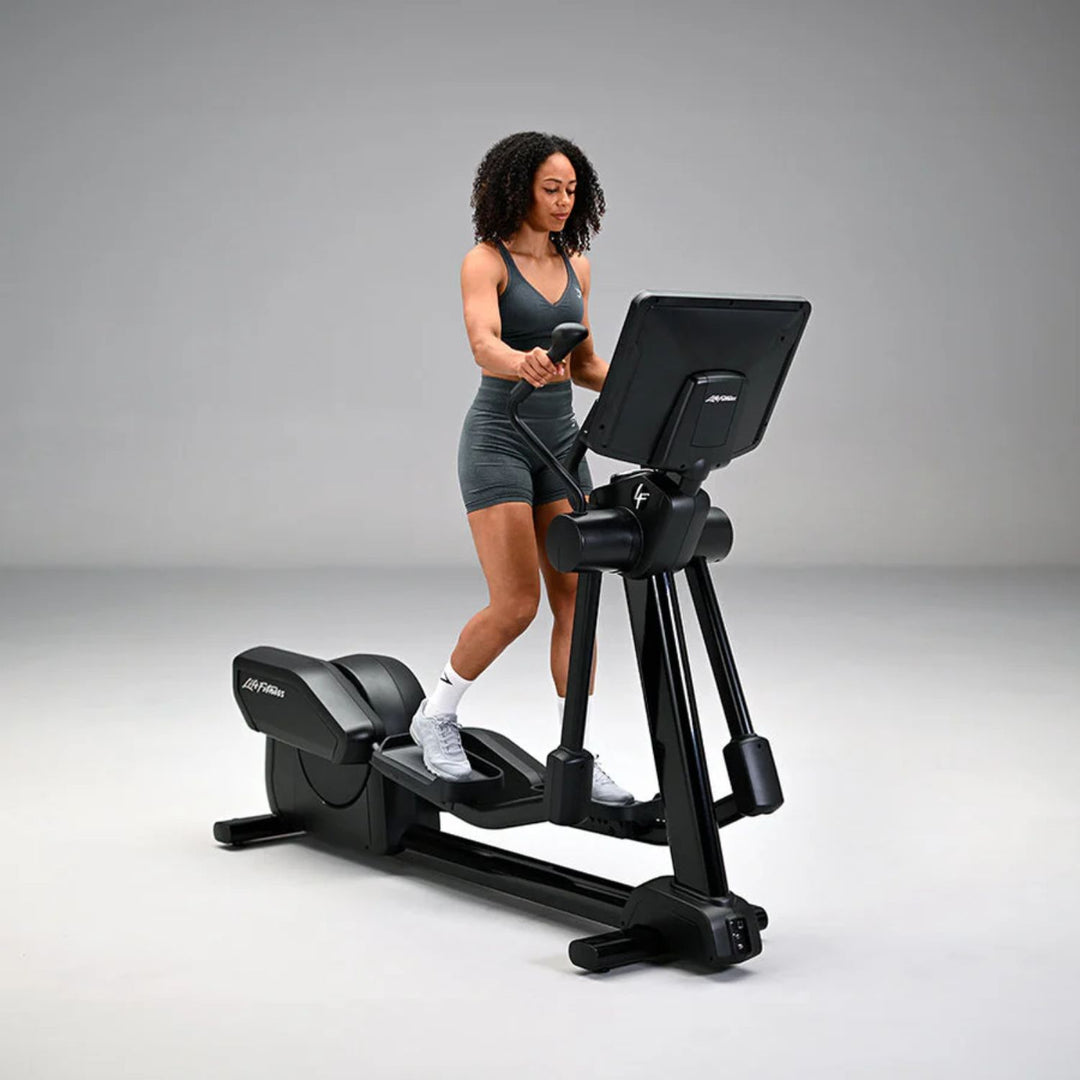 Woman using the Life Fitness Club Series Plus elliptical with SE4 console in black, demonstrating full-body cardio workout and natural stride motion
