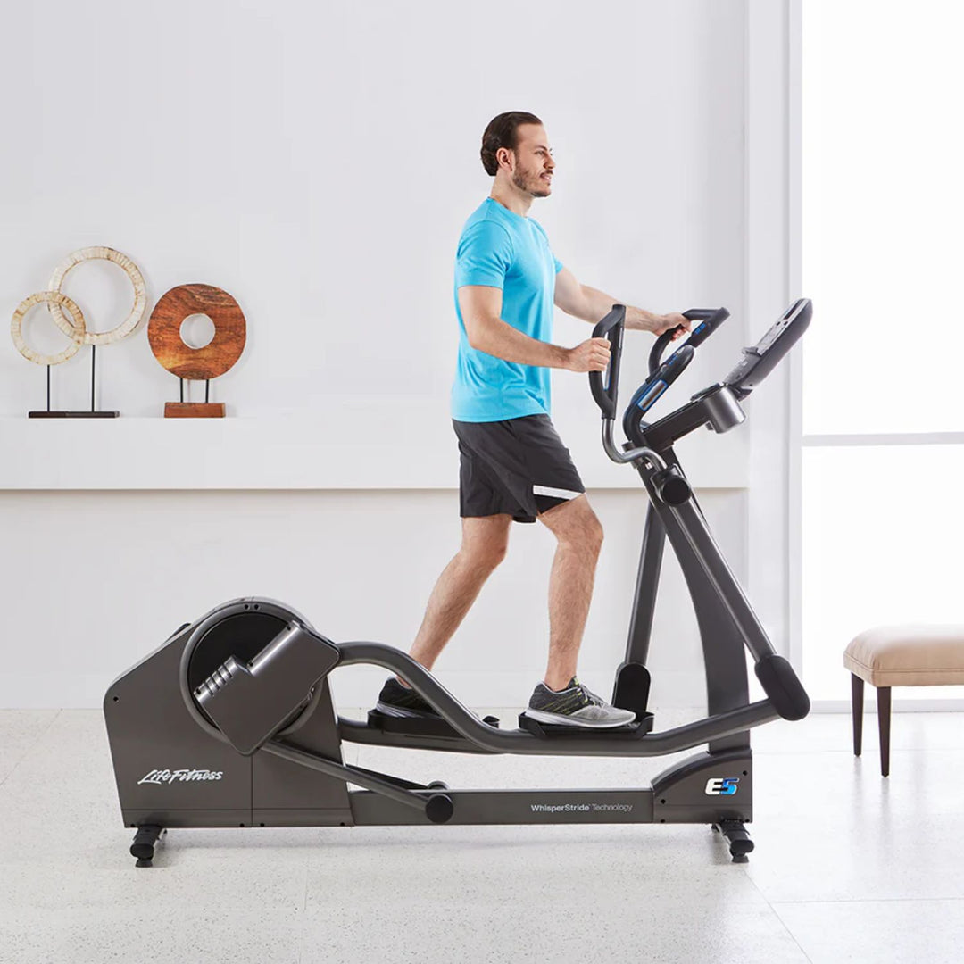 Man using Life Fitness E5 elliptical cross trainer in home setting demonstrating adjustable stride technology and smooth low impact cardio workout