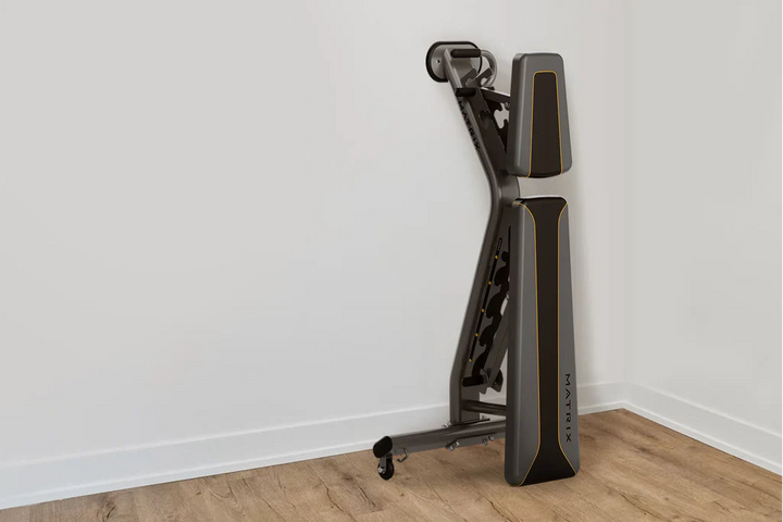 Matrix adjustable weight bench stored in vertical position showing compact space saving design for home gym use