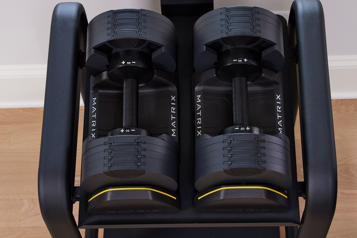 Matrix dumbbells placed on gym floor showing durable design and grip handles for versatile strength training workouts