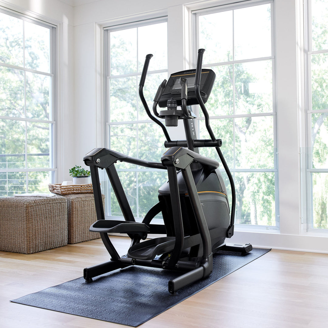 Matrix E30 elliptical in living room setting with back angle view showing compact design and smooth stride cardio use