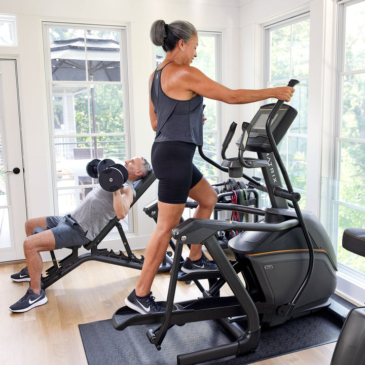 Male and female using Matrix elliptical in home setting with side profile view showing smooth stride cardio workout