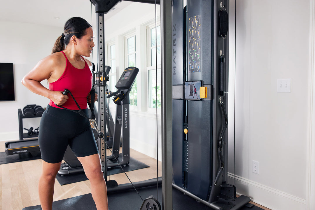 Female performing low row exercise on Matrix functional trainer using D handle with side angle close up view