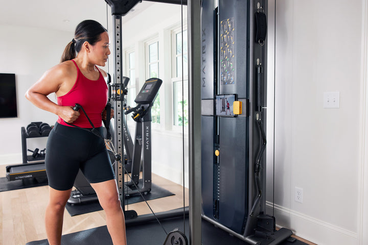 Female performing low row exercise on Matrix functional trainer using D handle with side angle close up view