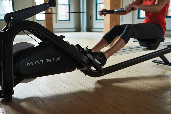 Person rowing on the Matrix magnetic rowing machine during exercise.
