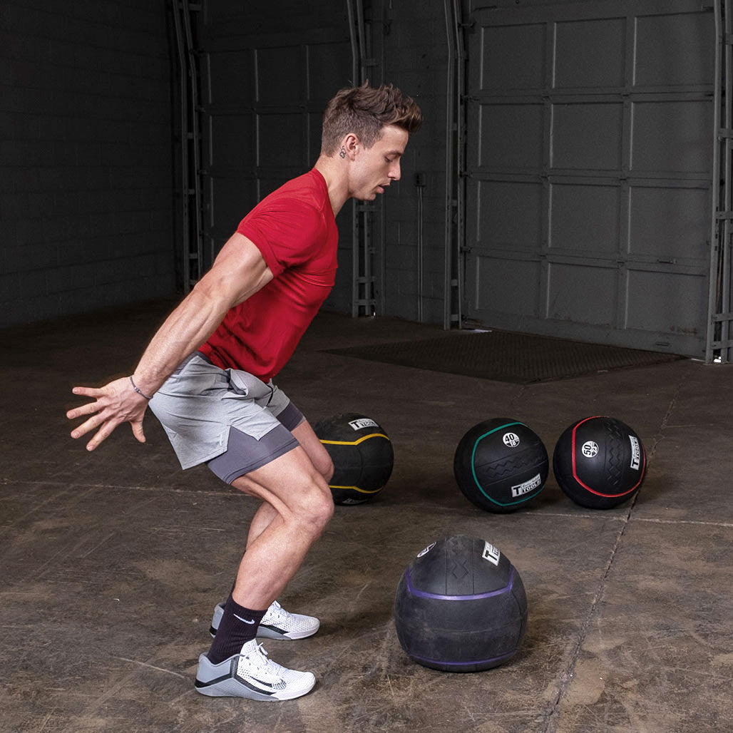Athlete performing a slam exercise using a heavy rubber medicine ball.