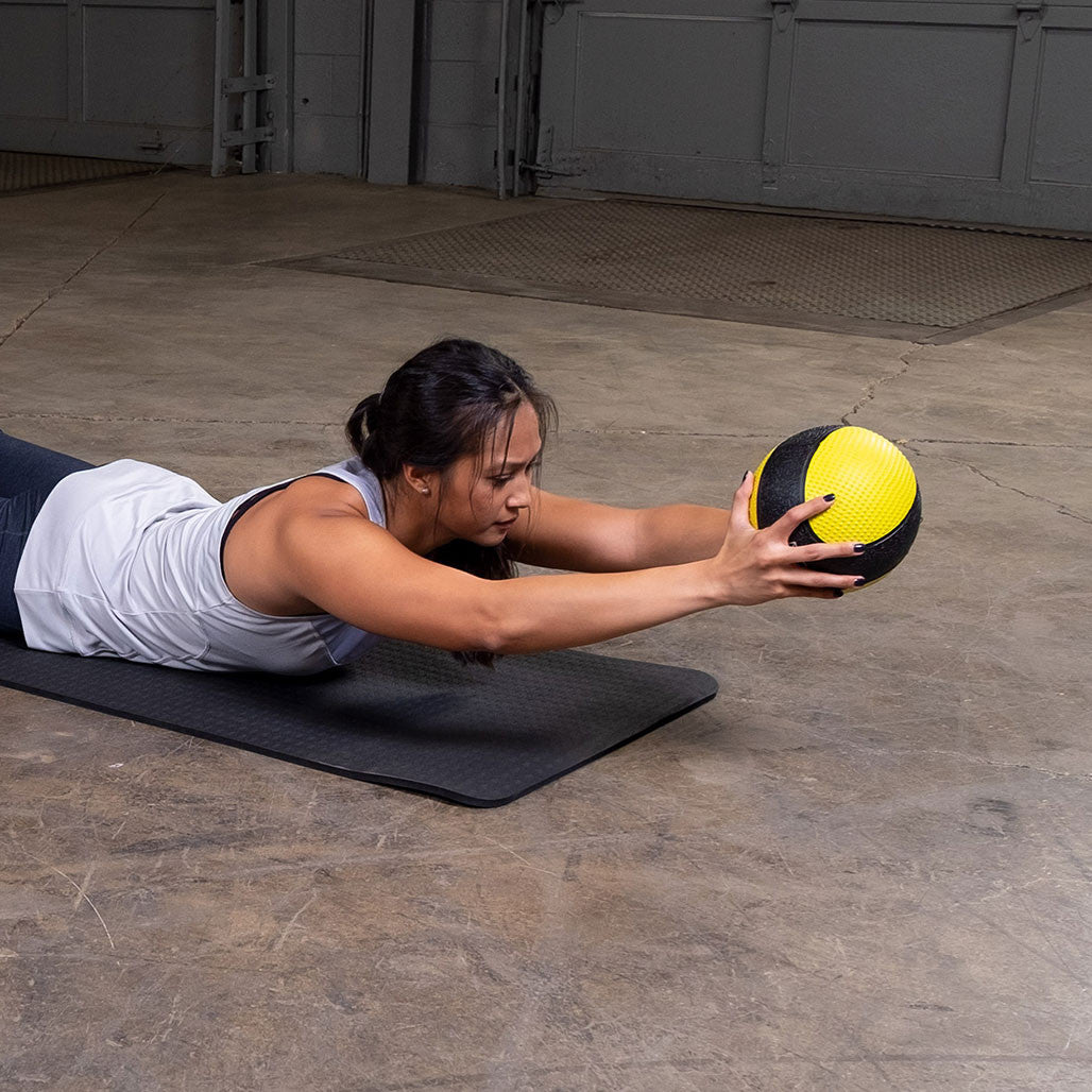 Athlete performing a Superman reach exercise with a premium medicine ball.