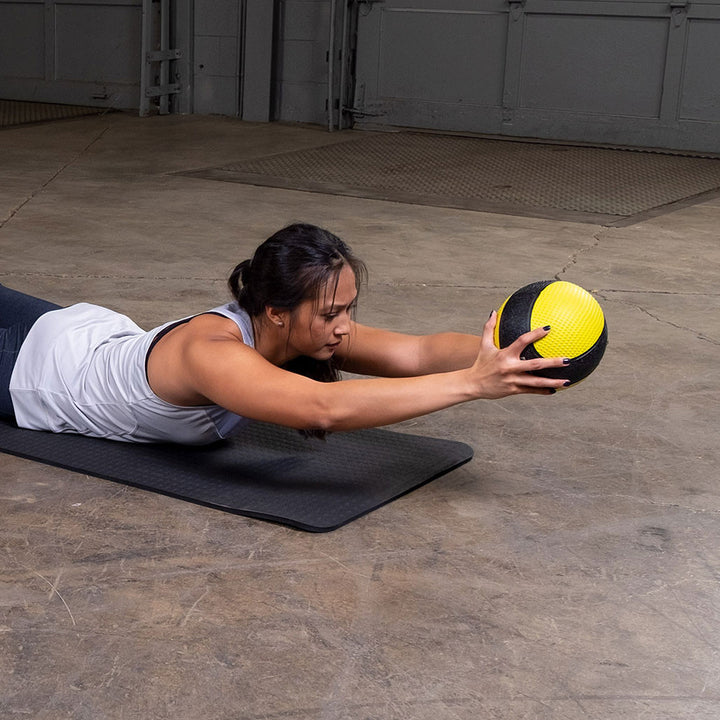 Athlete performing a Superman reach exercise with a premium medicine ball.