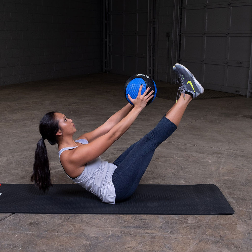 Athlete performing a V-up exercise with a premium medicine ball.
