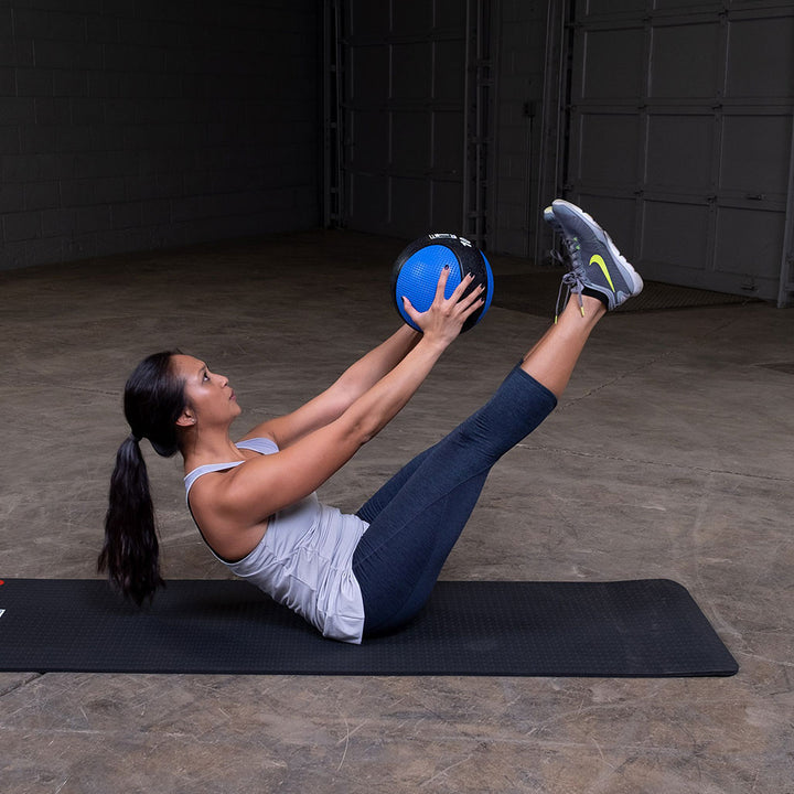 Athlete performing a V-up exercise with a premium medicine ball.
