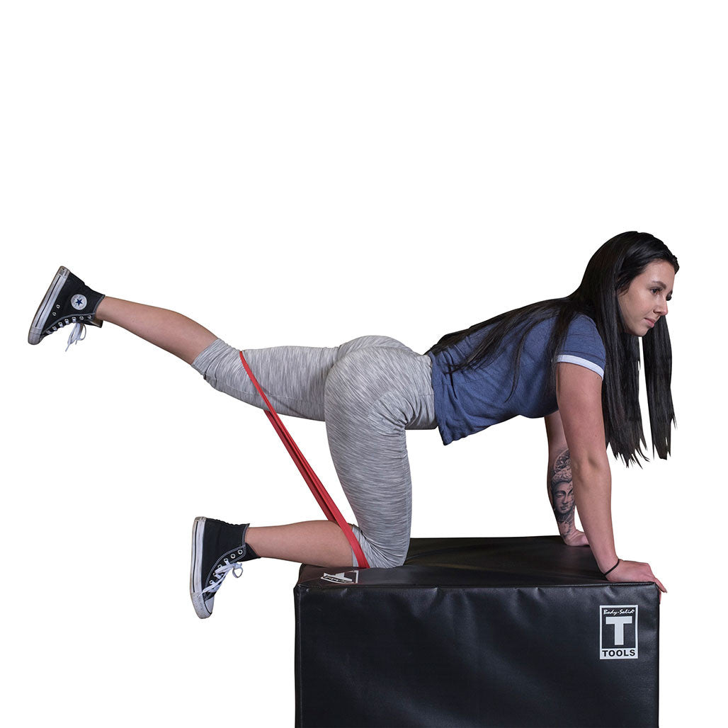 User performing a glute kickback exercise with a Body-Solid Tools mini resistance band.