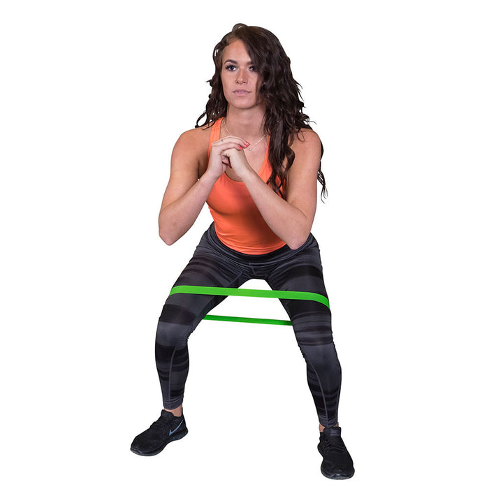 User performing a squat with a Body-Solid Tools mini resistance band around the thighs.