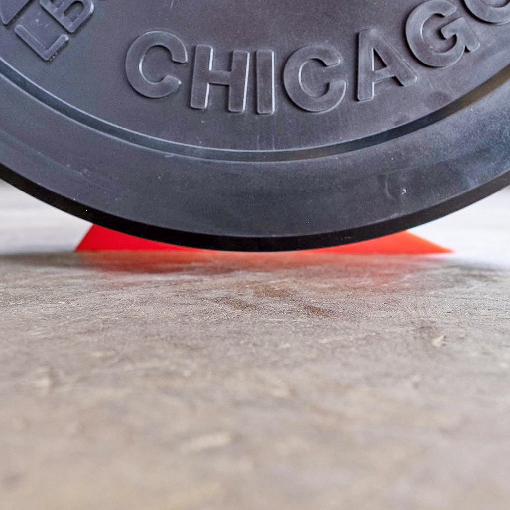 Close-up of the silicone deadlift wedge positioned beneath a weight plate.
