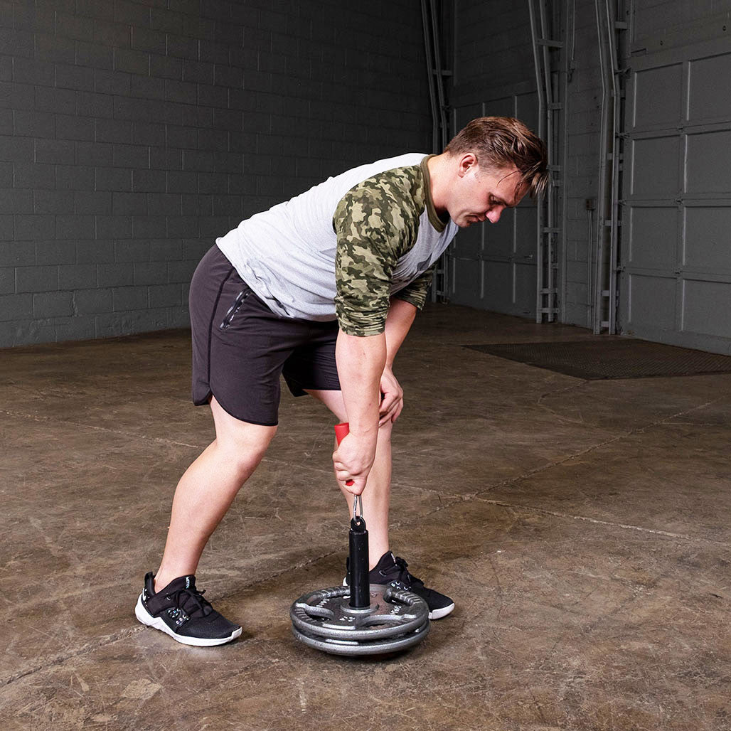 Person performing a farmer's walk using the Olympic lifting pin and weight plates.