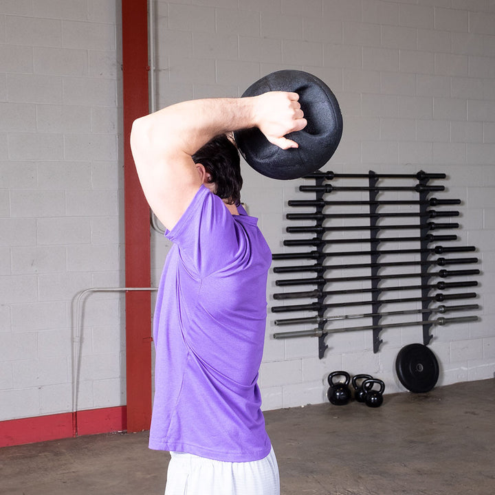 Person performing an overhead exercise using a Body-Solid dual grip medicine ball.