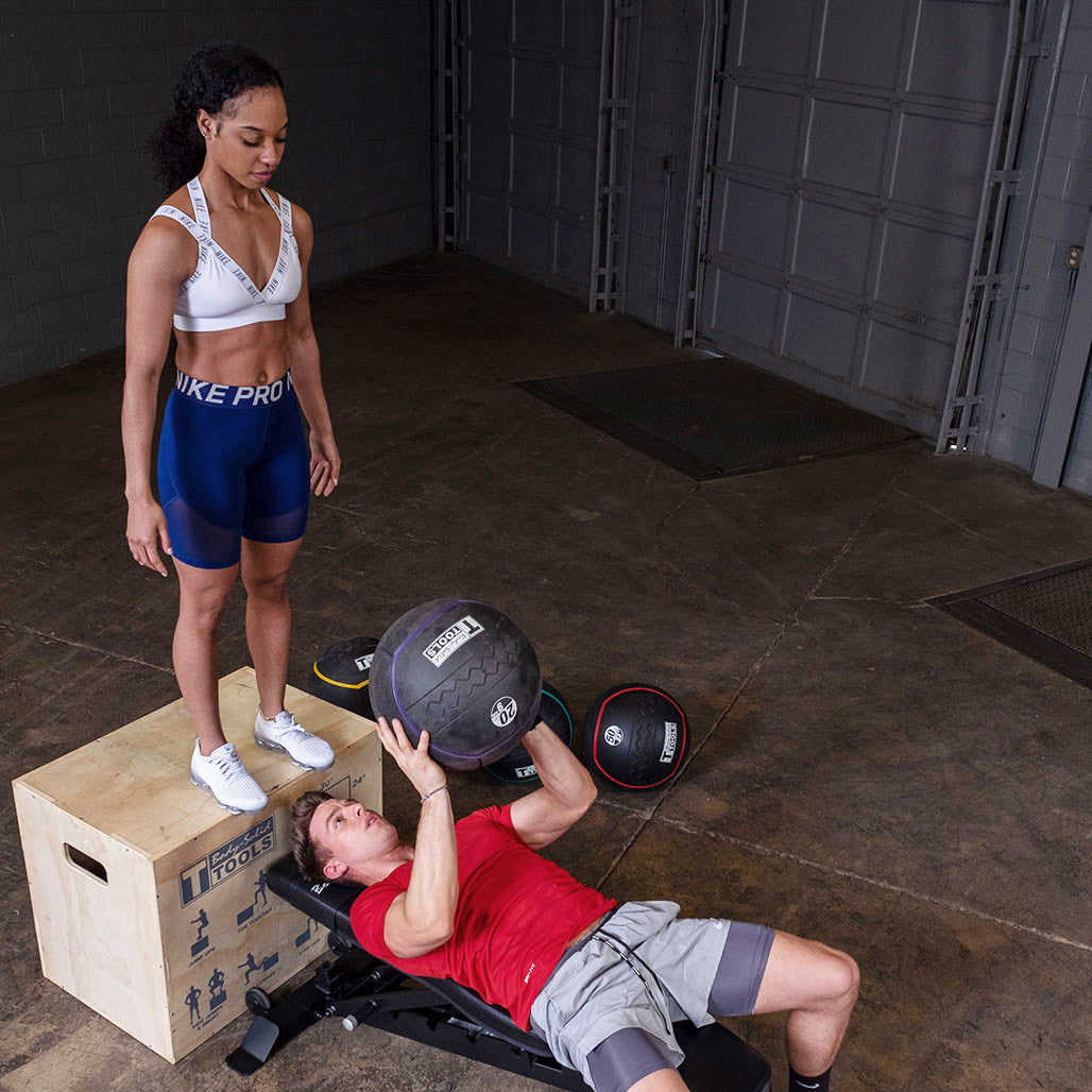 Two athletes performing a partner exercise with a heavy rubber medicine ball.